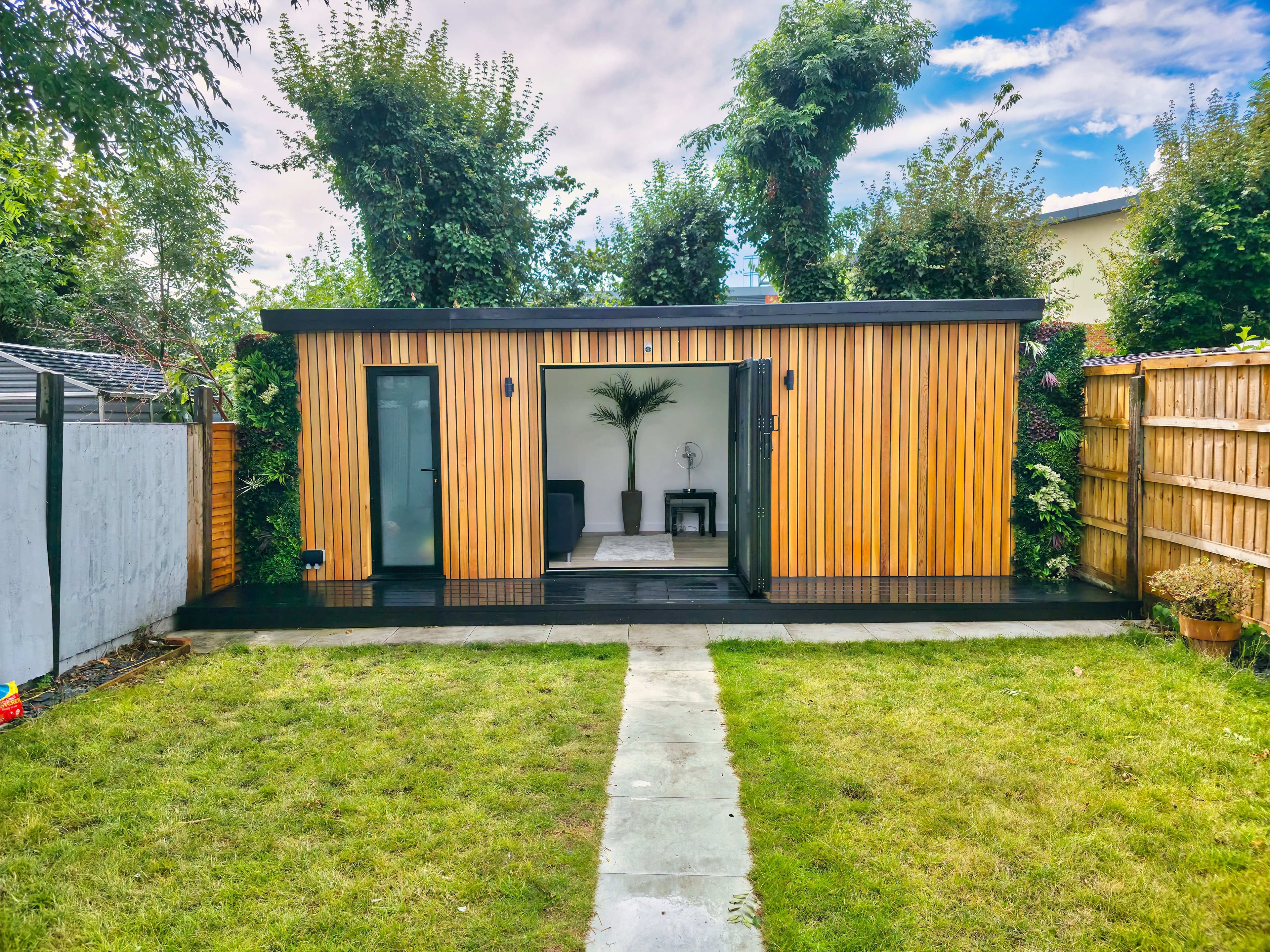 Cedar-clad garden room in Bedfordshire with living-wall planting and bifold doors open to a lounge