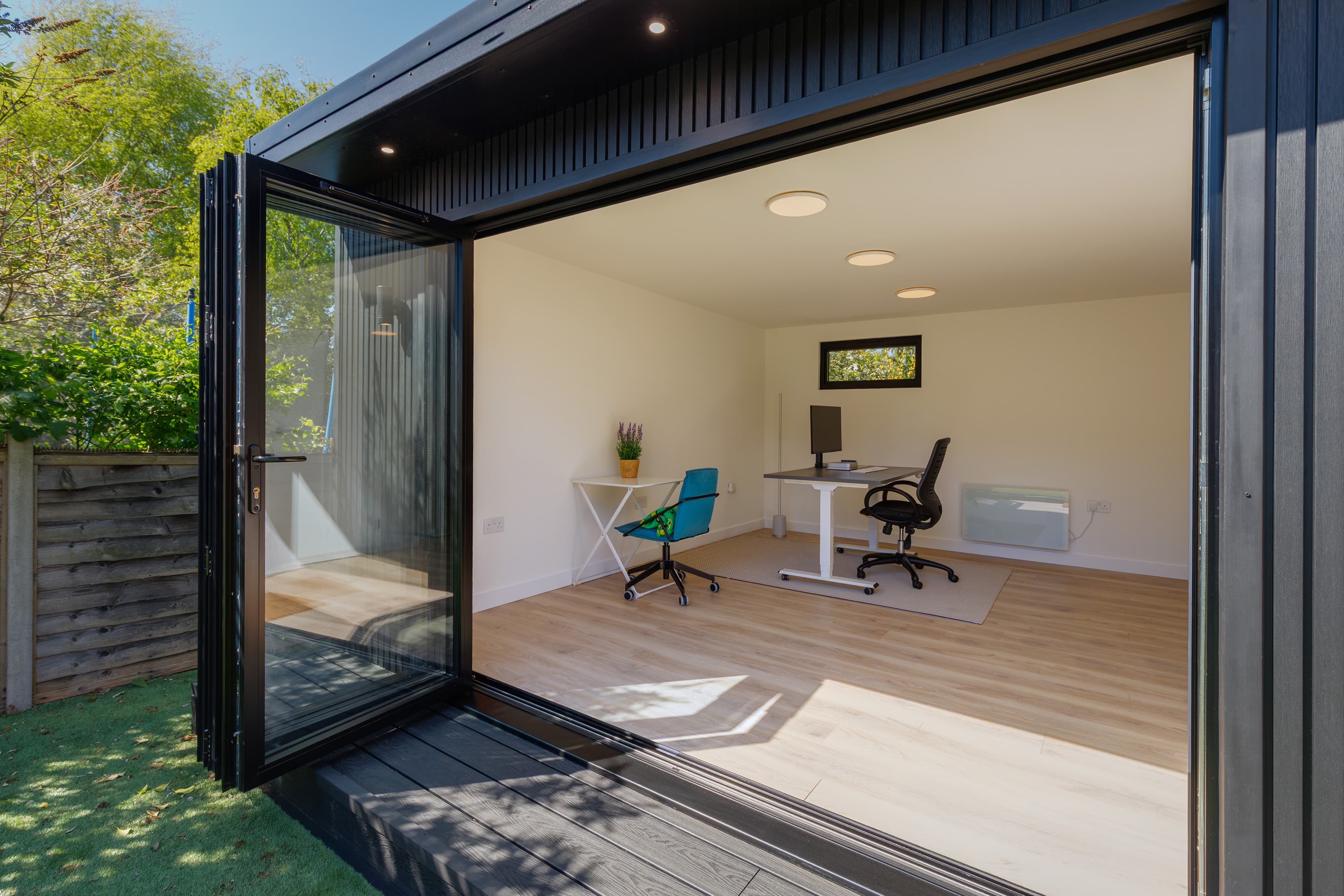 Garden office interior in Bedfordshire with bifold doors open to the garden and two desks on oak flooring