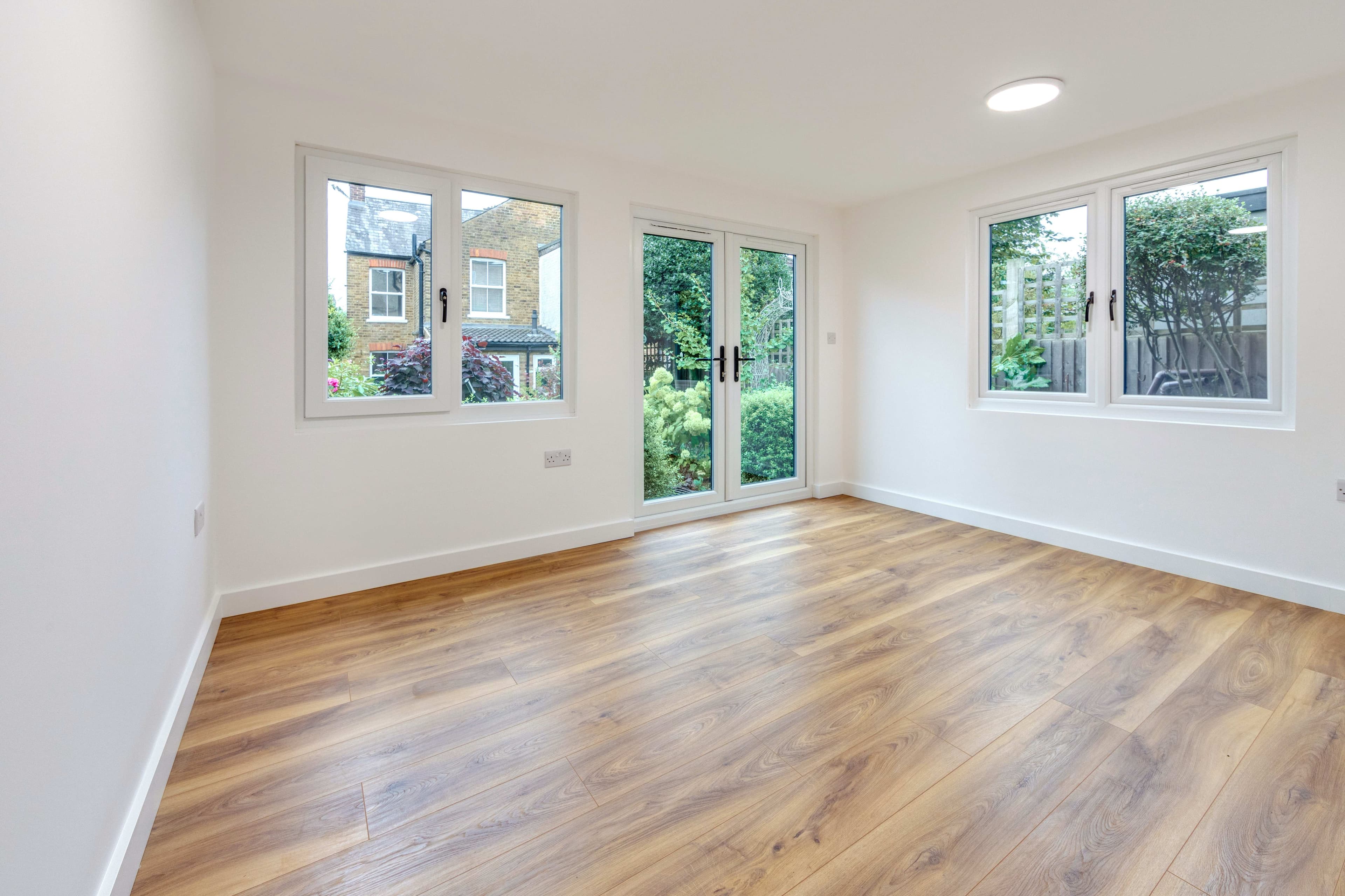 Garden room interior in Bedfordshire with oak flooring and white French doors opening to the garden