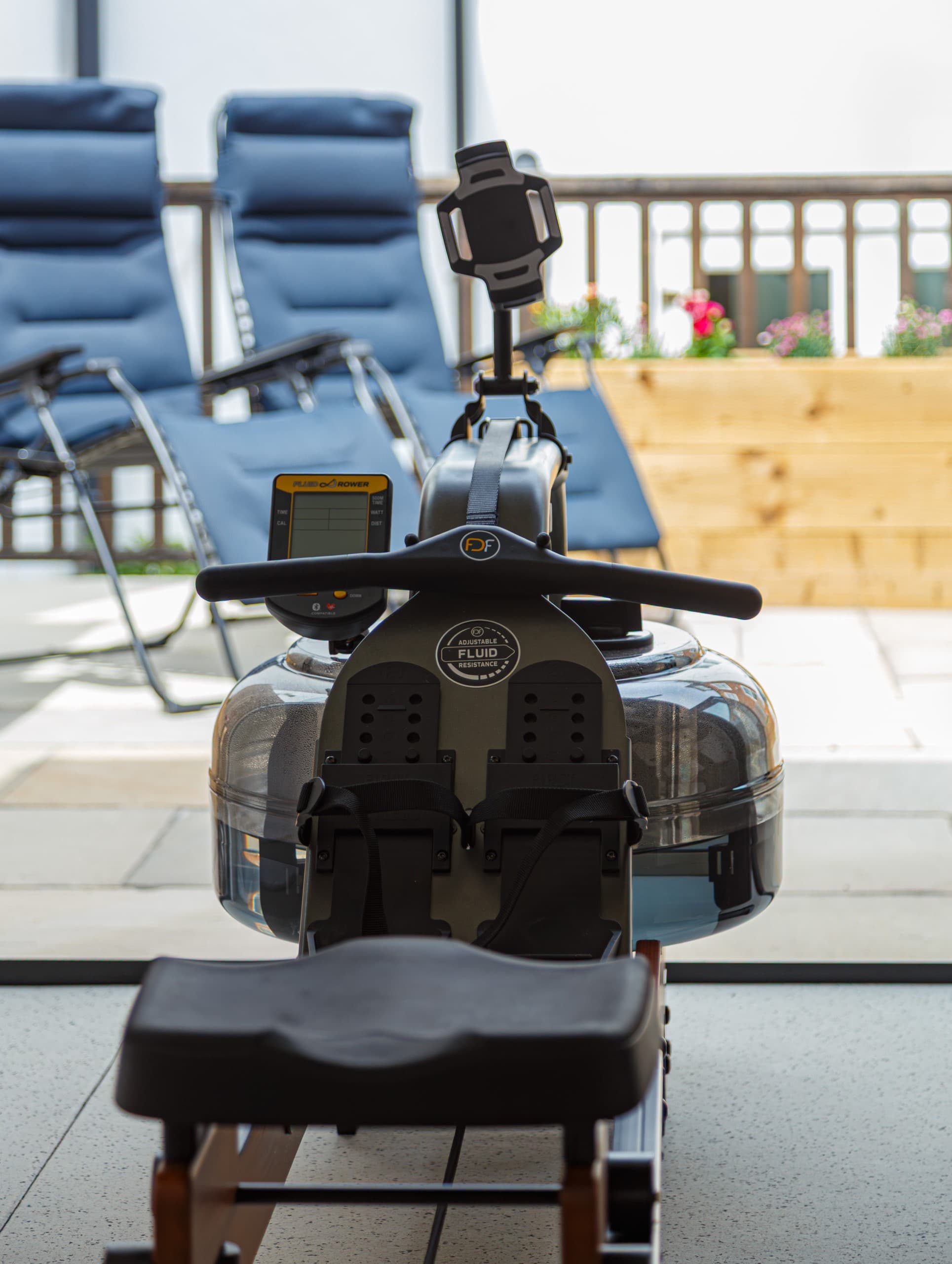 Water rowing machine on a Bedfordshire garden gym patio with reclining loungers and planters behind